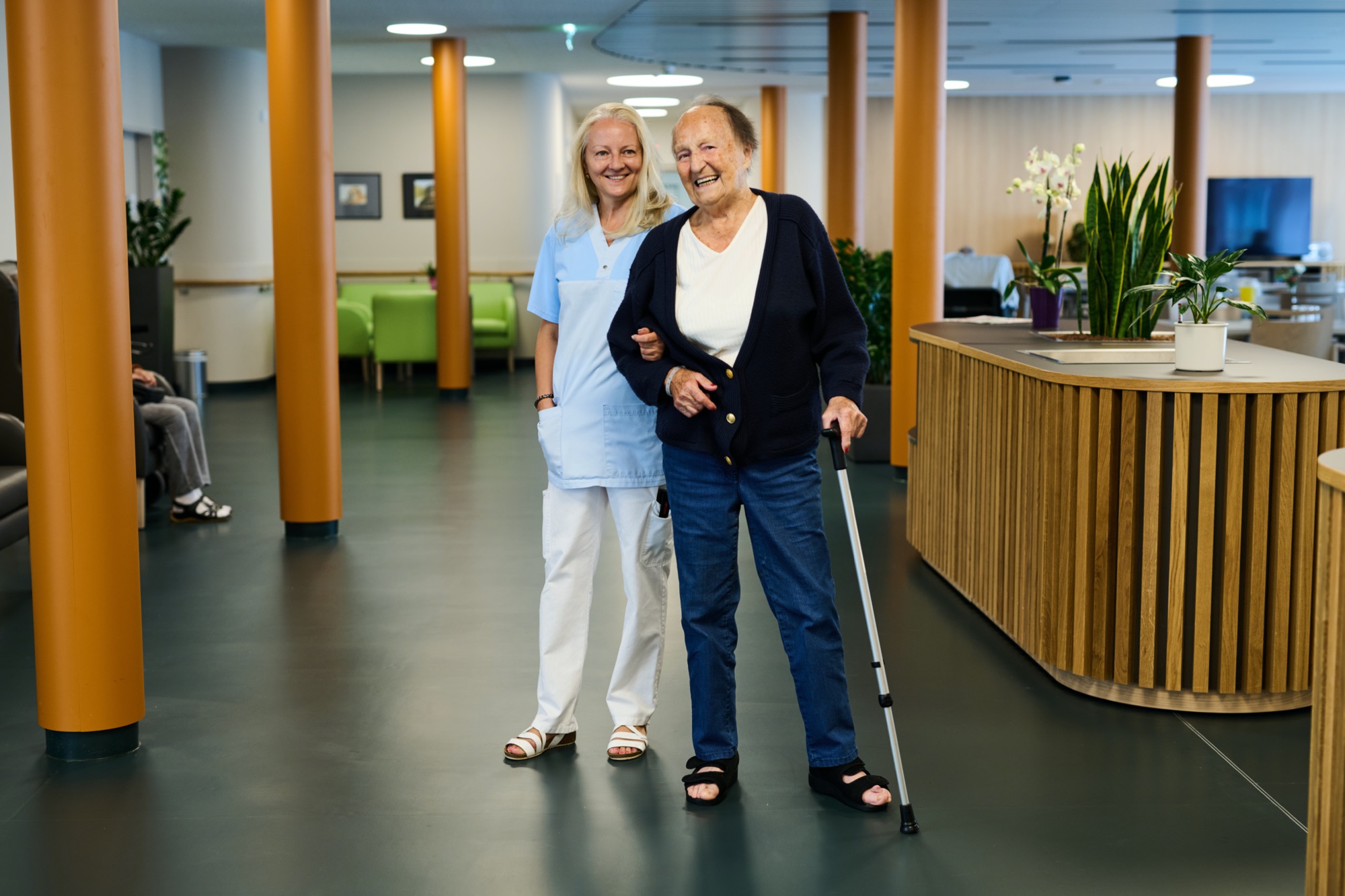 Eine Pflegerin mit einer älteren Person in einem Pensionisten-Wohnhaus