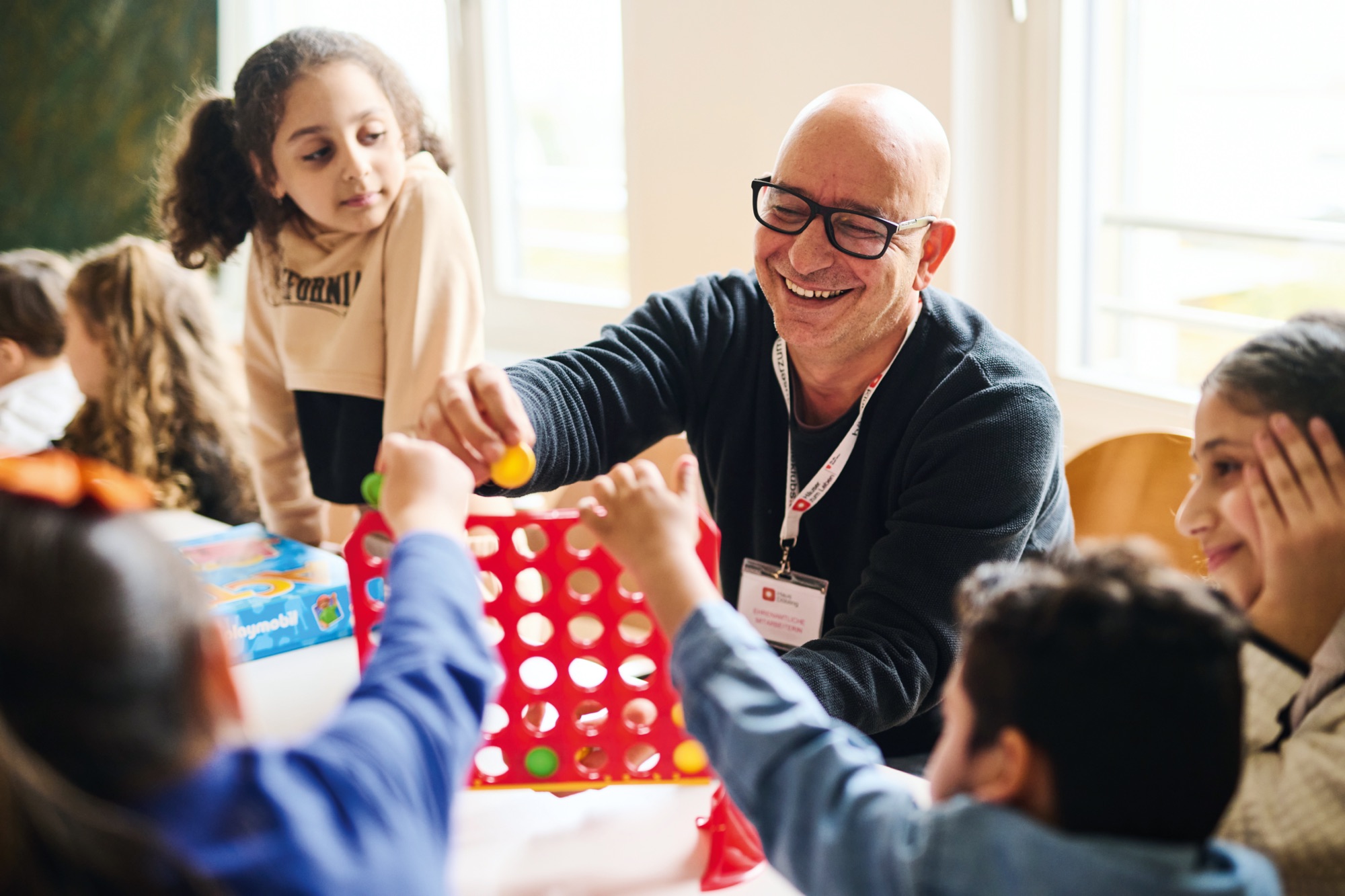 Ein Mann spielt mit Kindern "Vier gewinnt"