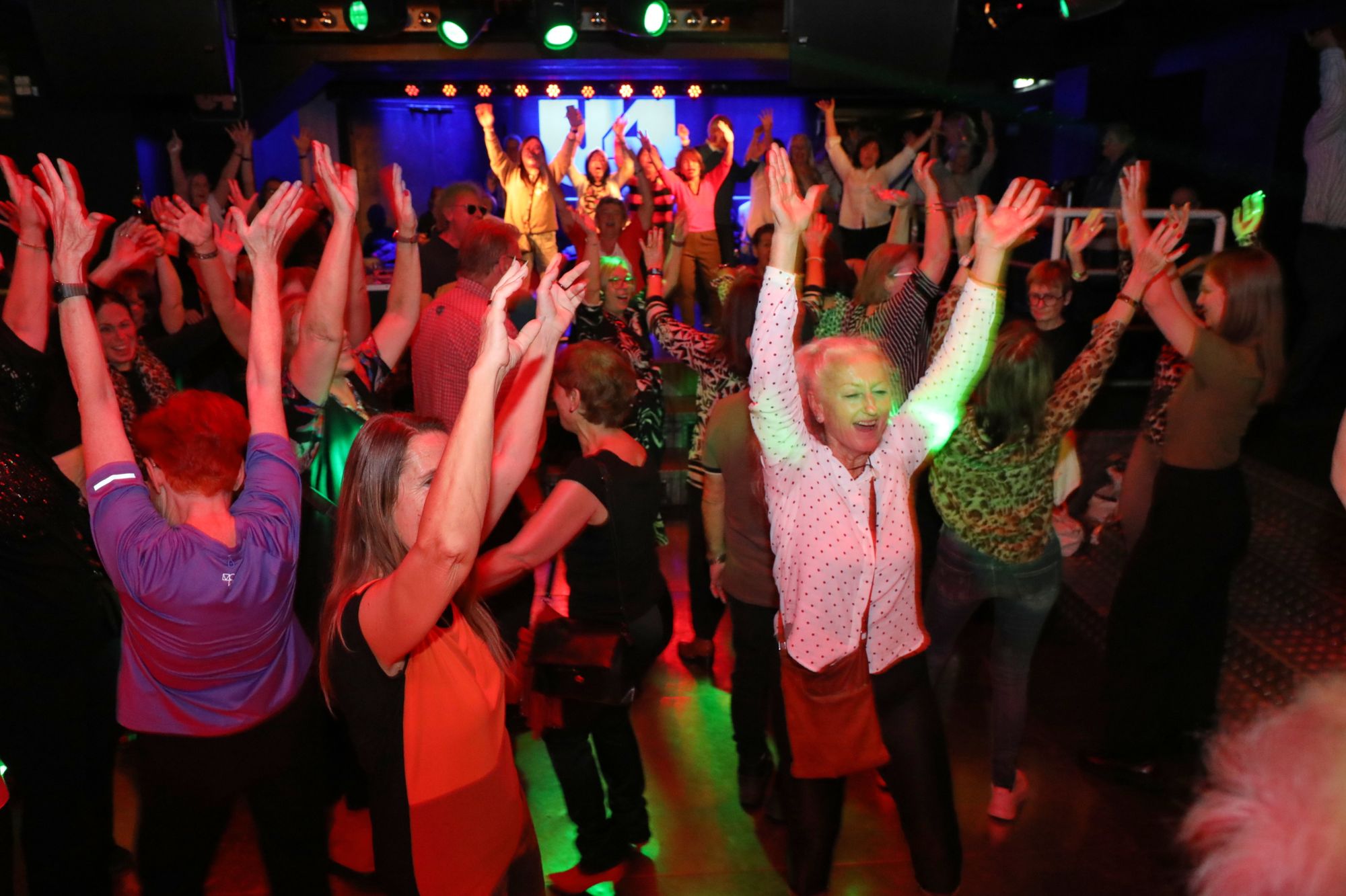 Mehrere Personen strecken die Hände in die Höhe und tanzen in der Disco U4.